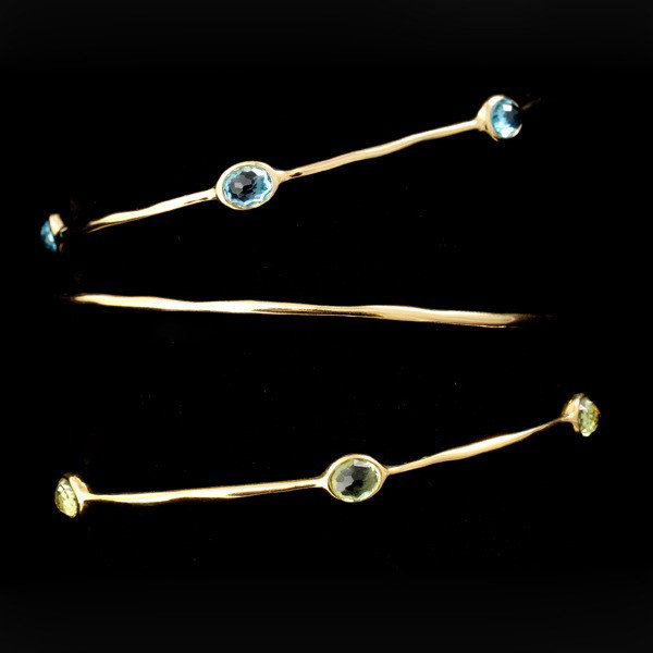 3 IPPOLITA MULTI-STONE, 18K YELLOW GOLD BRACELETS: COLLECTION OF IPPOLITA THREE MULTI-STONE, 18K YELLOW GOLD BRACELETS. Including one 18k yellow gold bangle featuring five oval peridots and one bangle featuring five oval blue topaz bezel set in 18k ye