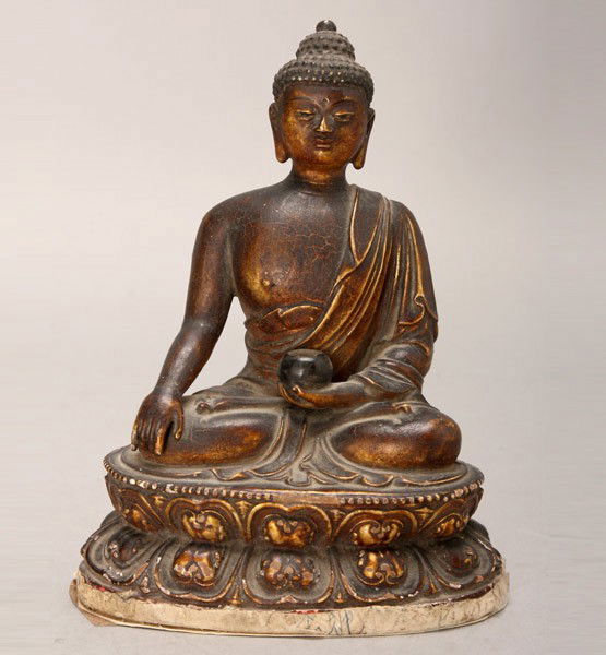 A Seated Sakyamuni: A Seated Sakyamuni, possibly made of plaster painted with gilt and dark brown lacquer, shown holding a beggar's bowl while seated upon a double lotus pedestal, displaying delicately rendered features