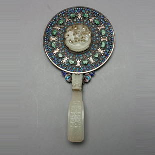 A Jade Mounted Hand Mirror, Qing Dynasty: A Jade Mounted Hand Mirror, The circular mirror back set with a central carved jade plaque depicting a figure standing on a large fish, surrounded by concentric patterns of finely enameled floral