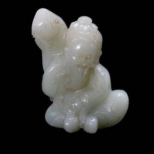 A Jade Figure with Fish: A Jade Figure with Fish, The robed and bearded figure with exaggerated earlobes, shown sitting while holding a massive fish above his right shoulder, displaying incised features and details. Height: