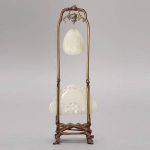 Two White Jade Carvings Mounted with a Wood Stand: Two White Jade Carvings Mounted with a Wood Stand, The first a chime form pendant carved with 'lingjiao' (horned water chestnut) and a lotus blossom below; the second a polished pebble hanging above