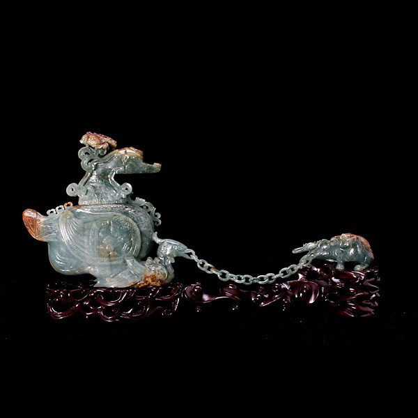 A Jade Carving of a Bird-Form Vase & Mythical Bea: A Green Jade Carving of a Bird-Form Vase and a Mythical Beast Connected by a Loose Chain, Of mottled deep green hues exhibiting russet inclusions, the vase depicting two birds with bats flying above, 