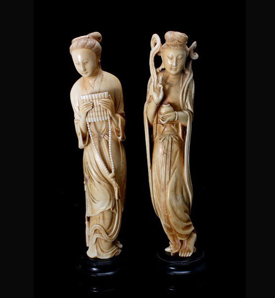 Two Carved Ivory Beauties*: Two Carved Ivory Beauties*, The first wearing a robe cinched at the waist by a tasseled belt and holding a flute with beaded decoration; the second adorned with a beaded necklace and billowing sashes 