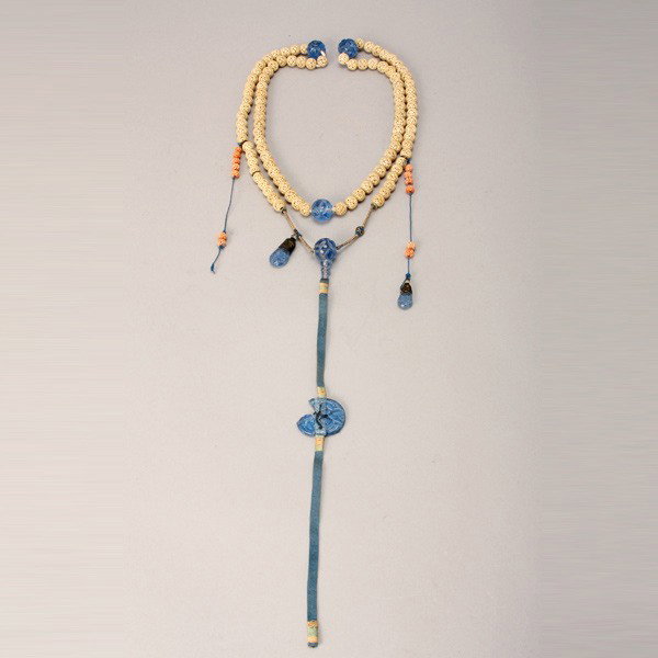 A Court Necklace*: A Court Necklace*, Comprising 98 reticulated ivory beads evenly spaced between three carved blue glass beads, a central drop tassel displaying additional glass beads, surrounded by two smaller tassels