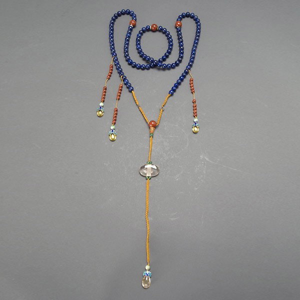 A Lapis Lazuli Court Necklace: A Lapis Lazuli Court Necklace, Composed of 119 lapis lazuli beads, interspaced by four japer beads flanked by jadeite discs; centering one drop tassel composed of carved rockcrystal quartz, carnelian,