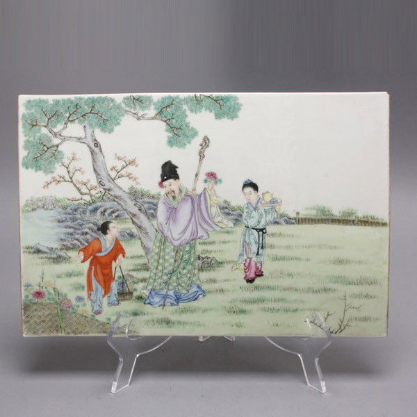 A Rectangular Porcelain Plaque: A Rectangular Porcelain Plaque, In horizontal format, depicting a male figure dressed in colorful robes with a black hat and holding a gnarled wood staff, accompanied by two attendants with either a f
