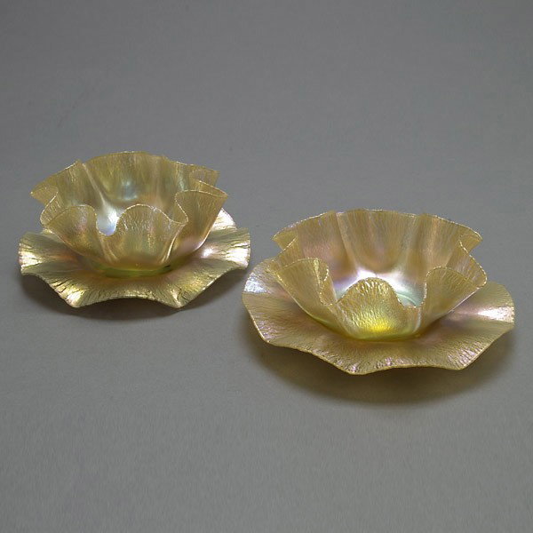 Two Tiffany Studios Favrile Stretch Bowls: Associated Pair of Tiffany Studios Favrile Stretch Bowls and Undertrays, Early 20th Century Each bowl with a wide ruffled rim in iridescent stretch glass with highlights, the undertrays with a rounded