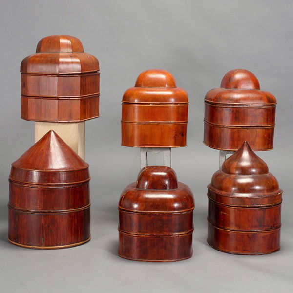A Group of Six Wood Hat Boxes: A Group of Six Wood Hat Boxes, each constructed with multiple stacking compartments, various lobed covers with some ascending to a pointed element or domed top {Tallest: 19 inches (48.3 cm)} [cracks,