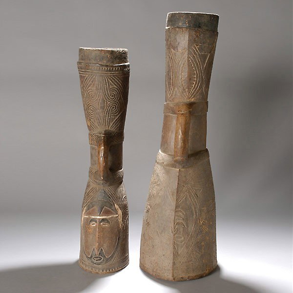 PNG Sepik river tribal art kundu drum: Two BOIKEN hand drums (kundu), Papua New Guinea. Carved heavy hardwood, each with abstract faces. Height of one 31 inches. Both in good condition.