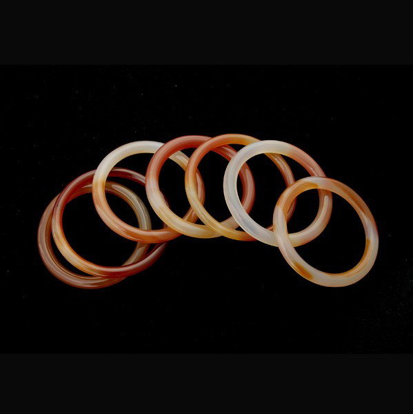 COLLECTION OF SEVEN CARVED CARNELIAN BANGLES.: COLLECTION OF SEVEN CARVED CARNELIAN BANGLES. The carved carnelian bangles range in sizes measuring approximately 6.00 mm to 8.00 mm in depth and with internal diameter from 54.00 mm to 60.00 mm.