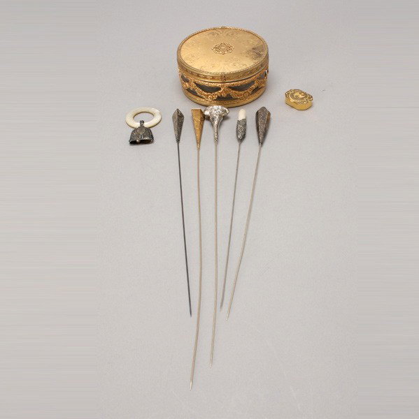 5 Hatpins; baby rattle; pill box; dresser jar: Five Hatpins: two marked sterling; together with a sterling baby rattle with mother of pearl ring; a gilt metal pill box; and a dresser jar (8) {Diameter of jar 4 1/2 inches}
