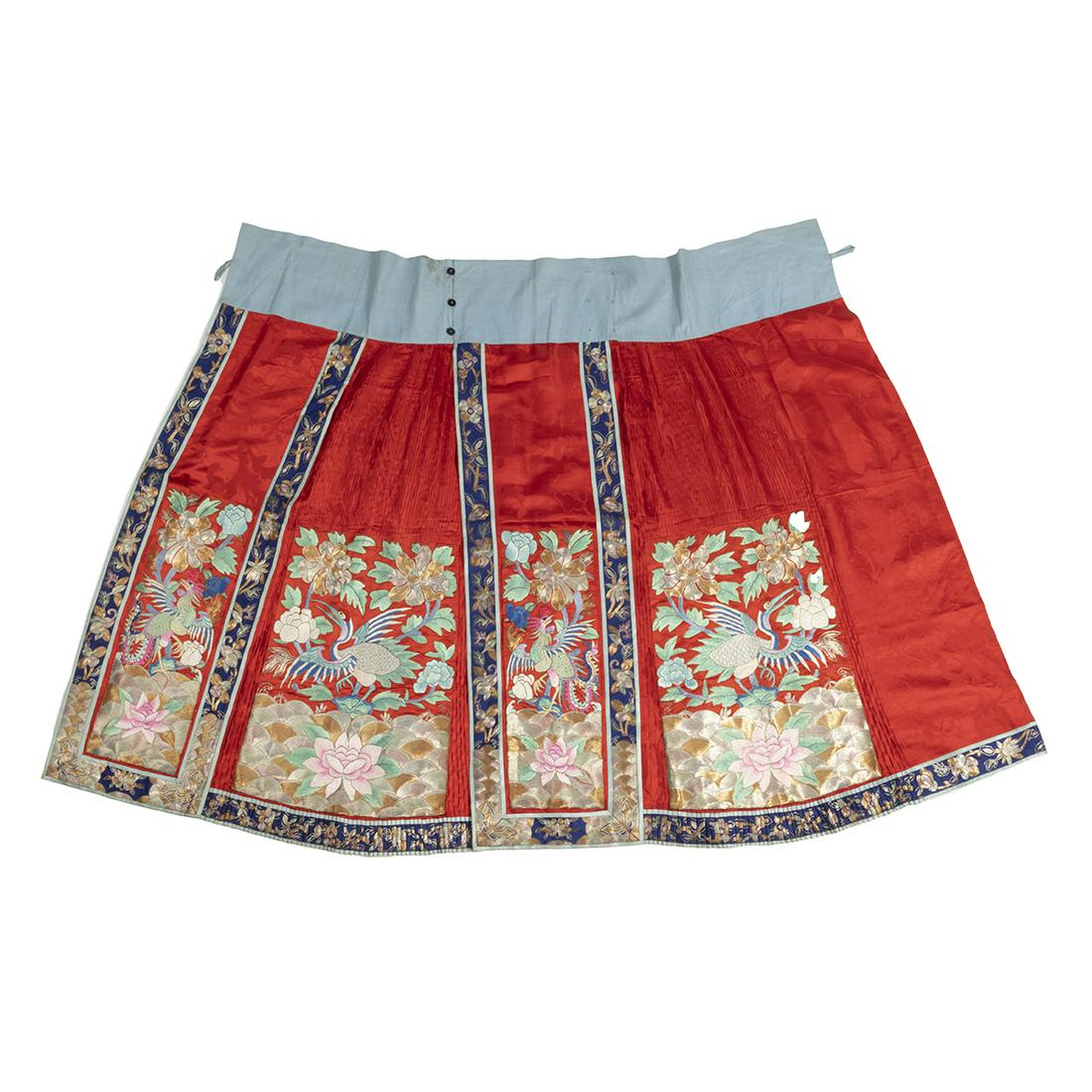A Chinese Red Ground Silk Pleated Skirt: A Chinese Red Ground Silk Pleated Skirt. A red ground pleated skirt embroidered with couched metallic and gilt-wrapped threads, featuring peonies, lotus, phoenix, butterfly, and cloud motifs within li