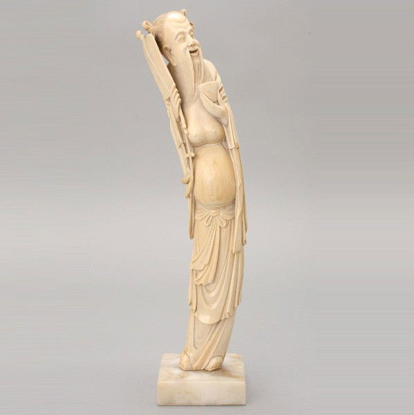 An Ivory Carving of Zhongli Quan*: An Ivory Carving of Zhongli Quan*, The standing immortal dressed in long flowing robes, shown carrying his unique attributes, highlighted with black pigment, attached to a square marble base. Republic