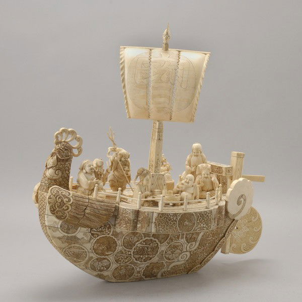 A Massive Pieced Ivory and Bone Boat with Figures: A Massive Pieced Ivory and Bone Boat with Figures*, The ship carved with the Seven Gods of Good Luck on deck, surrounded by their various attributes, the sail decorated with a stylized Shou character,