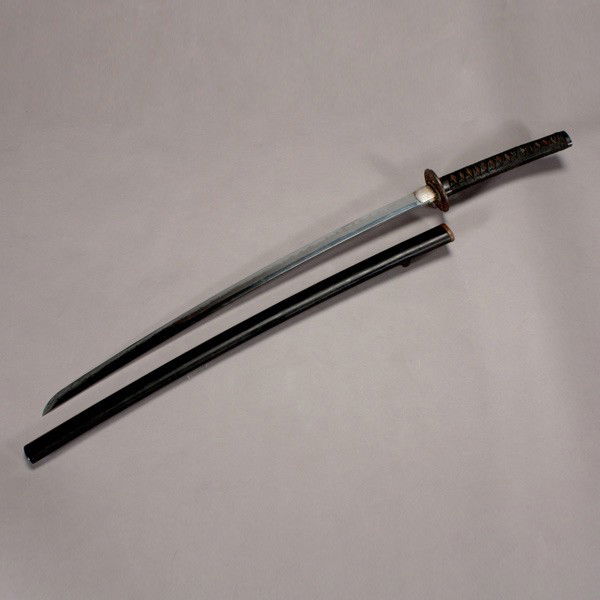 A Japanese Katana, Meiji Period: A Katana, The blade of very shallow curve, with a black lacquered wood scabbard, a gilt-metal guard cast with figures, a metal collar, two gilt-metal ornaments, a faux sting ray leather binding, and a