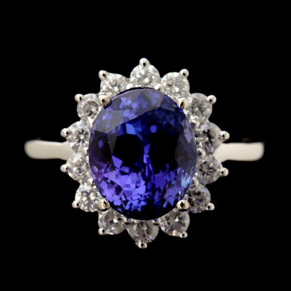 TANZANITE, DIAMOND, 14K WHITE GOLD RING.: TANZANITE, DIAMOND, 14K WHITE GOLD RING. Featuring one oval tanzanite weighing a total of approximately 4.34 ct., surrounded by fourteen full-cut diamonds weighing a total of approximately 0.81 ct., i