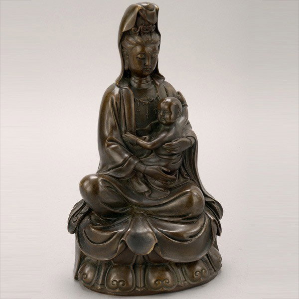 A Bronze Guanyin with Child: A Bronze Guanyin with Child, shown seated while wearing her characteristic hooded garment and holding a child, raised upon a lotus pedestal {Height: 12 1/2 inches (31.7 cm)} [Abrasions, minor nicks an