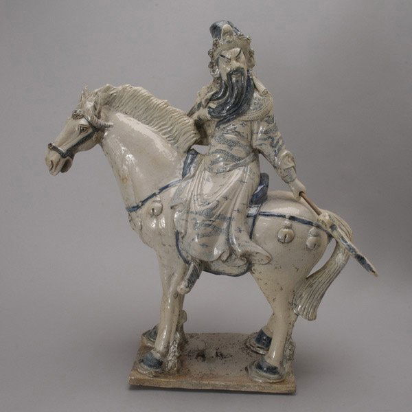 A Large Blue and White Porcelain Guandi on a Horse: A Large Blue and White Porcelain Figure of Guandi on a Horse, the equine form shown standing with its rider bearing a long bladed weapon while wearing elaborate garments, a mark to the back of the sad