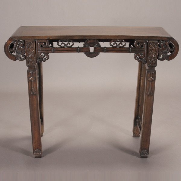 A Hardwood Altar Table: A Hardwood Altar Table, rolled ends carved with dragon heads and flowers, openwork aprons of coin design and the legs carved with leafy scrolls {35 x 45 x 15 inches (89 x 114.5 x 38 cm)} [Abrasions, o