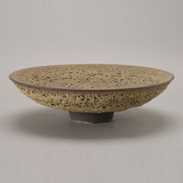 James Lovera Gray and Brown Crater Bowl: James Lovera (American Born 1920) The wide shallow stoneware bowl with an allover gray and brown crater glaze on a brown slip glazed recessed foot, inscribed on base "Lovera 75", paper label "75-6". M