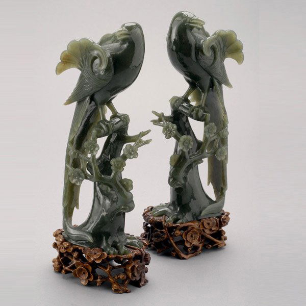 A Pair of Spinach Jade Birds: A Pair of Spinach Jade Birds, Each bird perched on a flowering prunus tree with its head turned and long tail gently curving around the tree trunk, each feather carved in relief and highlighted with i