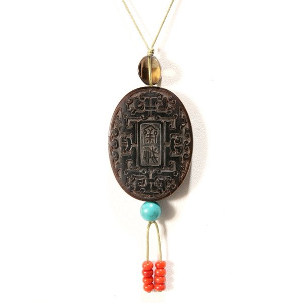 A Rare Rhinoceros Horn Pendant*: A Rare Rhinoceros Horn Pendant*, The oval plaque pierced through the center from top to bottom for suspension, well-carved in low relief to one side with the two characters 'zhai jie' and to the other