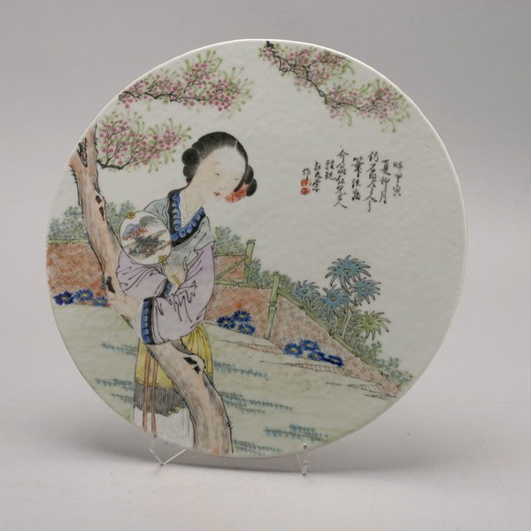 A Famille Rose-Enameled Plaque, Signed Wang Youta: A Famille Rose-Enameled Plaque, Of circular shape, the plaque painted in famille rose to depict a female beauty holding a circular painted fan while leaning against a flowering tree in a garden settin