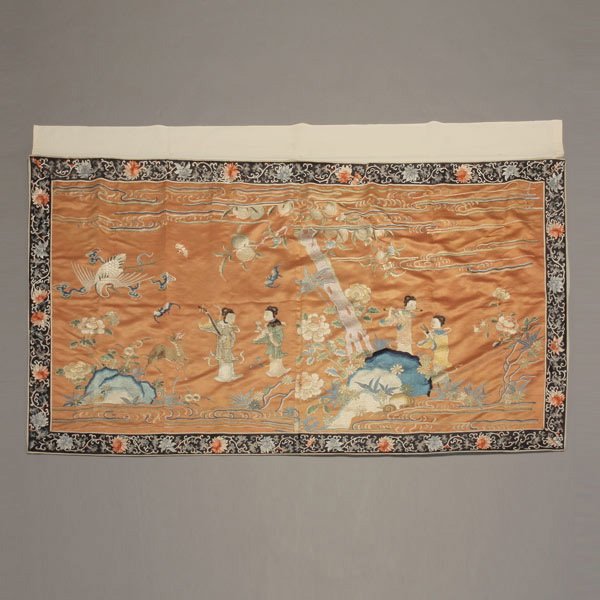 An Embroidered Figural Wall Hanging, Late Qing: An Embroidered Figural Wall Hanging, Showing a group of female musicians standing in a lush garden setting beneath a large peach tree, accompanied by a flying crane, bats and prancing deer amidst larg