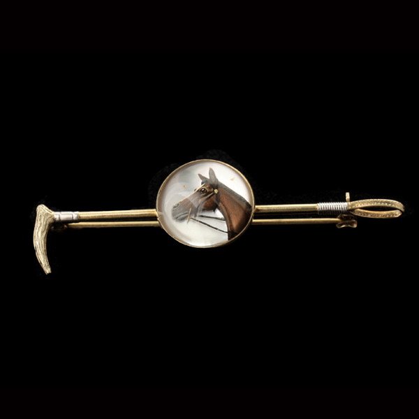 REVERSE INTAGLIO, 14K YELLOW GOLD EQUESTRIAN PIN.: REVERSE INTAGLIO, 14K YELLOW GOLD EQUESTRIAN PIN. Featuring one reverse intaglio depicting a horse, set in a 14k yellow gold riding crop mounting. 3.0 dwts
