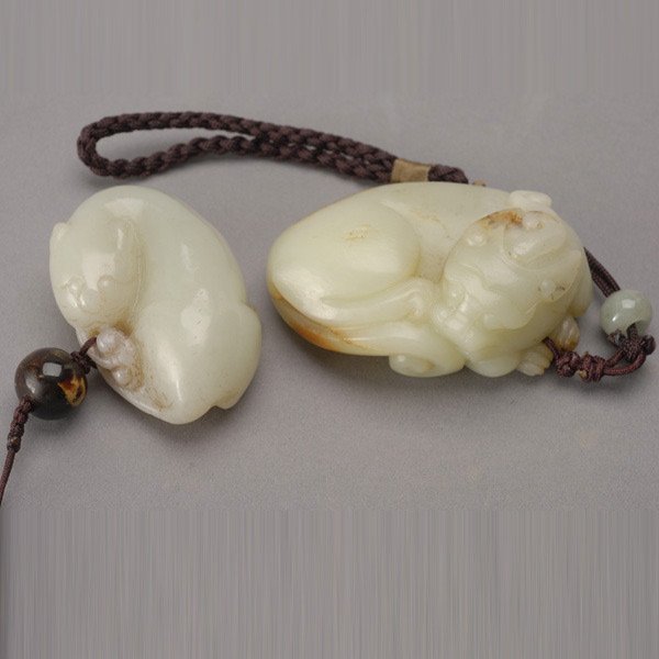 Two Carved Jade Beasts: Two Carved Jade Beasts, both depicting a recumbent lion-form beast with its tail tucked, and with a tassel attached {Longest: 2 5/8 inches (6.7 cm)}