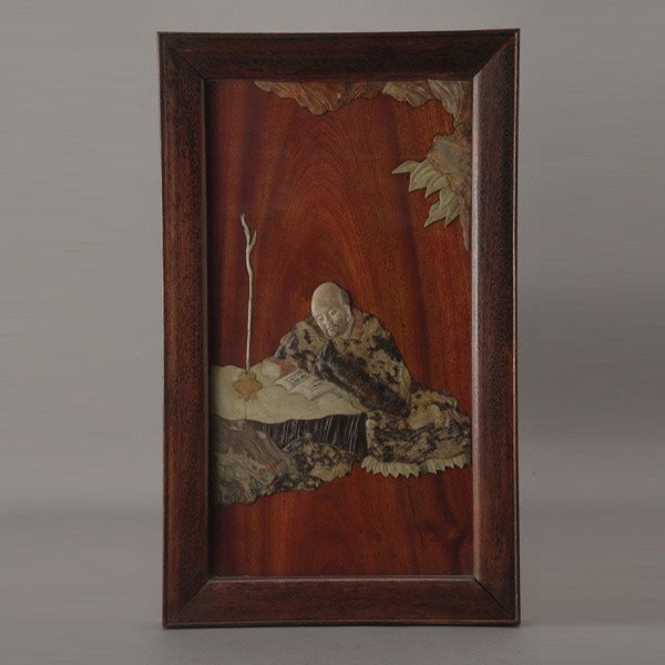 A Japanese Soapstone Embellished Wall Plaque: A Japanese Soapstone Embellished Wall Plaque, depicting a seated scholar leaning upon rockwork while reading {25 1/2 x 15 1/2 (64.7 x 39.4 cm)}
