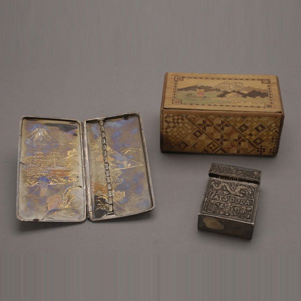 Three Boxes: two Japanese: Three Boxes: two Japanese, one polychrome engraved metal, the other an inlaid wood puzzle box; together with a silver metal cigarette box {Dimensions of wood box 2 3/4 x 6 x 3 3/4 inches} [Dents and l