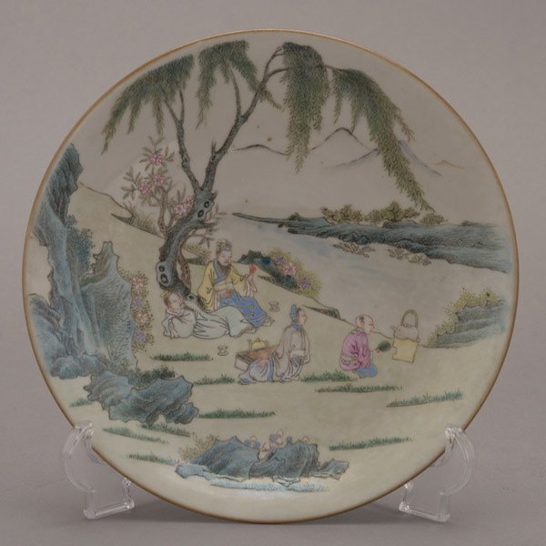 A Famille Rose-Enameled Dish: A Famille Rose-Enameled Dish, depicting figures upon a river bank beneath a willow tree, a mark to the base {Diameter: 9 1/4 inches (23.5 cm)}