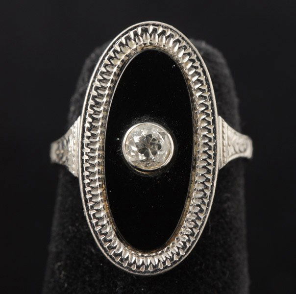 DIAMOND, BLACK ONYX, 14K WHITE GOLD RING.: DIAMOND, BLACK ONYX, 14K WHITE GOLD RING. Centering one old European-cut diamond, weighing approximately 0.15 ct., set in an oval black onyx tablet, set in a 14k white gold mounting. Size 4 1/2, 4.90