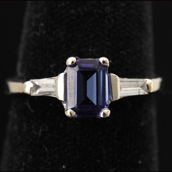 TANZANITE, DIAMOND, 14K WHITE GOLD RING.: TANZANITE, DIAMOND, 14K WHITE GOLD RING. Centering one emerald-cut tanzanite weighing approximately 0.80 ct., flanked by two baguette-cut diamonds weighing a total of approximately 0.30 ct., set in a