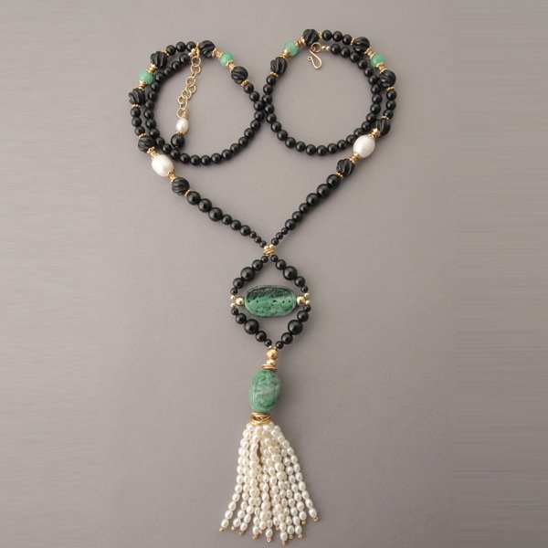 JADE, CULTURED PEARL, BLACK ONYX, METAL NECKLACE.: JADE, CULTURED PEARL, BLACK ONYX, YELLOW GOLD, METAL NECKLACE. Featuring one carved jadeite bead measuring approximately 22 x 18 mm, suspending a multi-strand cultured pearl tassel, attached to a grad