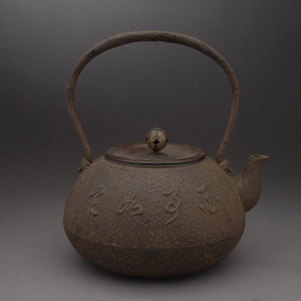 A Japanese Cast Iron Tea Kettle: A Japanese Cast Iron Tea Kettle, the lid with a fruit form finial and a mark to the underside, one side with an inscription {Height: 8 inches (20.3 cm)} [Rusting]