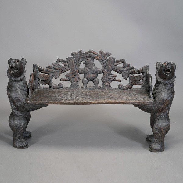 Black Forest Bear Bench: Black Forest Bear Bench. The arch form seat back elaborately carved with a bear atop a fallen tree trunk with large leaves, his arms spread out balancing on twin tree branches, the plank seat gouged t