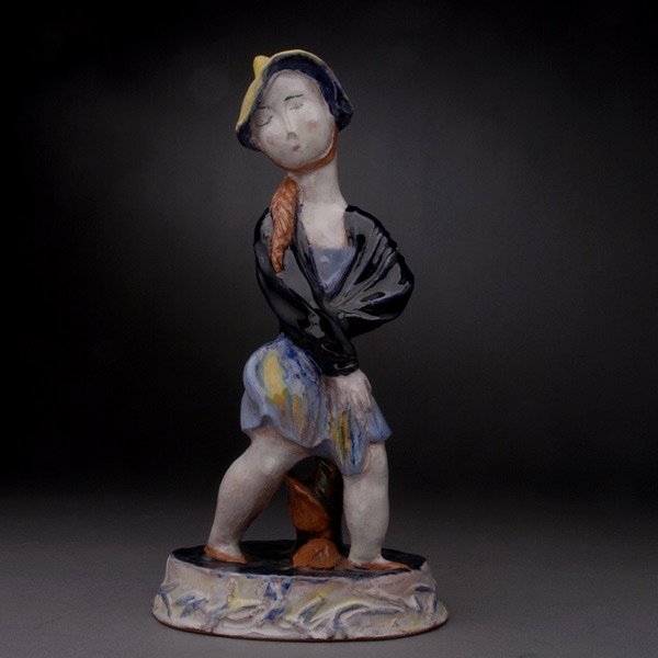 Wiener Werkstatte Pottery Figure of A Lady: Wiener Werkstatte Pottery Figure of A Lady. Modeled as a red haired lady wearing a conical yellow hat with a blue flambe glazed short skirt revealing her large calves, standing contraposto in front of