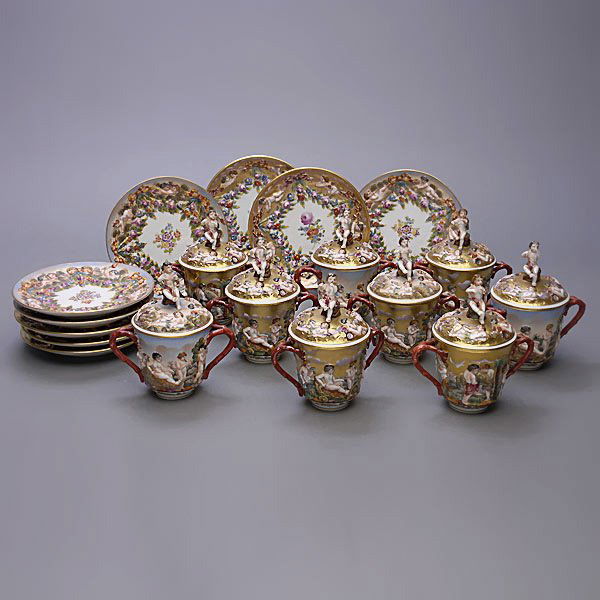 Nine Capodimonte Two Handled Covered Cups: Set of Nine Capodimonte Figural Two Handled Covered Cups and Saucers {Height of cups with covers 5 1/2 inches}