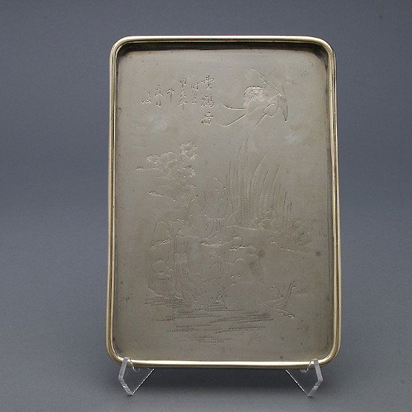 An Incised White Metal Tray: An Incised White Metal Tray, depicting two figures beneath a crane and an inscription, the back with a signature {Length: 8 3/8 inches (21.5 cm)} [Abrasions and dents]