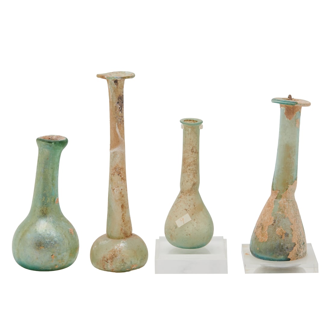 Collection of Roman Glass Vessels: Collection of Roman Glass Vessels.; Comprising pale blue example with everted mouth, elongated neck, and round tapered body, plastic stand included; smaller example to previous with similar form and p