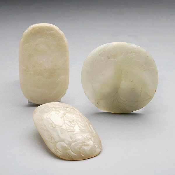 Three Jade Plaques: Three Jade Plaques, The first of circular form carved in relief with a pair of leafy peaches and two bats; the second of oval form carved in relief to depict two bearded gentlemen in a mountainous set