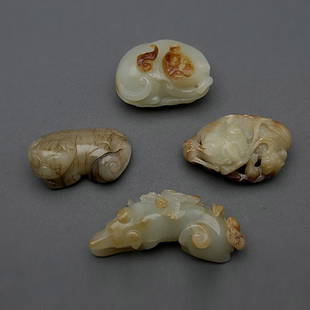 Four Jade Animal Carvings: Four Jade Animal Carvings, Consisting of a dog resting upon leafy foliage, two recumbent lion groups, and a reclining badger with a bat on its back, each carving suffused with russet inclusions. Longe