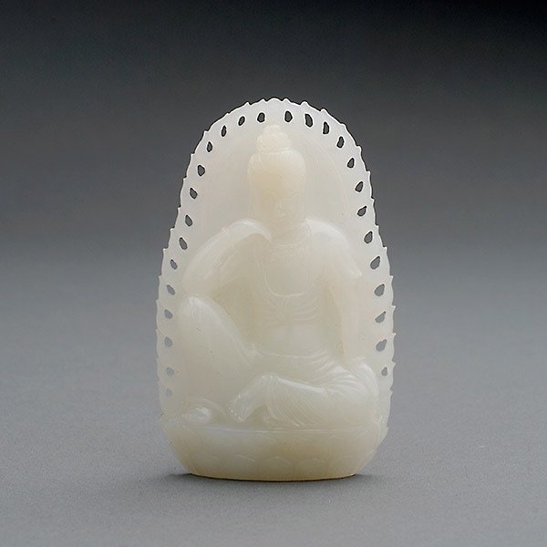 A White Jade Figural Pendant: A White Jade Figural Pendant, Carved in high relief to depict Guanyin seated in contemplation upon a lotus base, before a flaming mandarla, the stone of a creamy-white tone. Length: 2 1/2 inches (6.3 