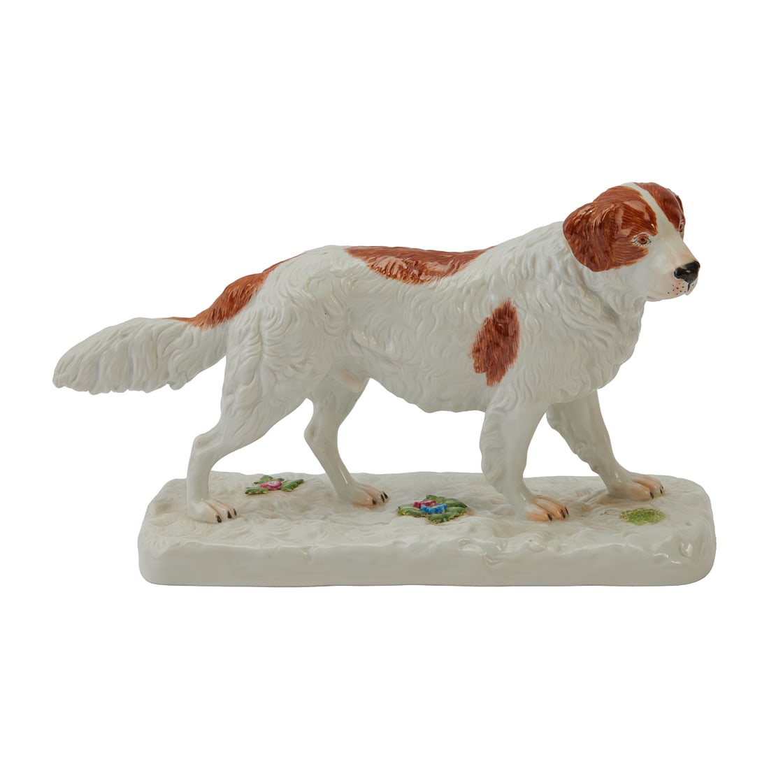 Meissen Porcelain Figure of a Saint Bernard Dog: Meissen Porcelain Figure of a Saint Bernard Dog, modelled standing on all four legs, facing dexter, tail lightly extended, on a low mounded, rounded rectangular base with applied florettes. The dog pa
