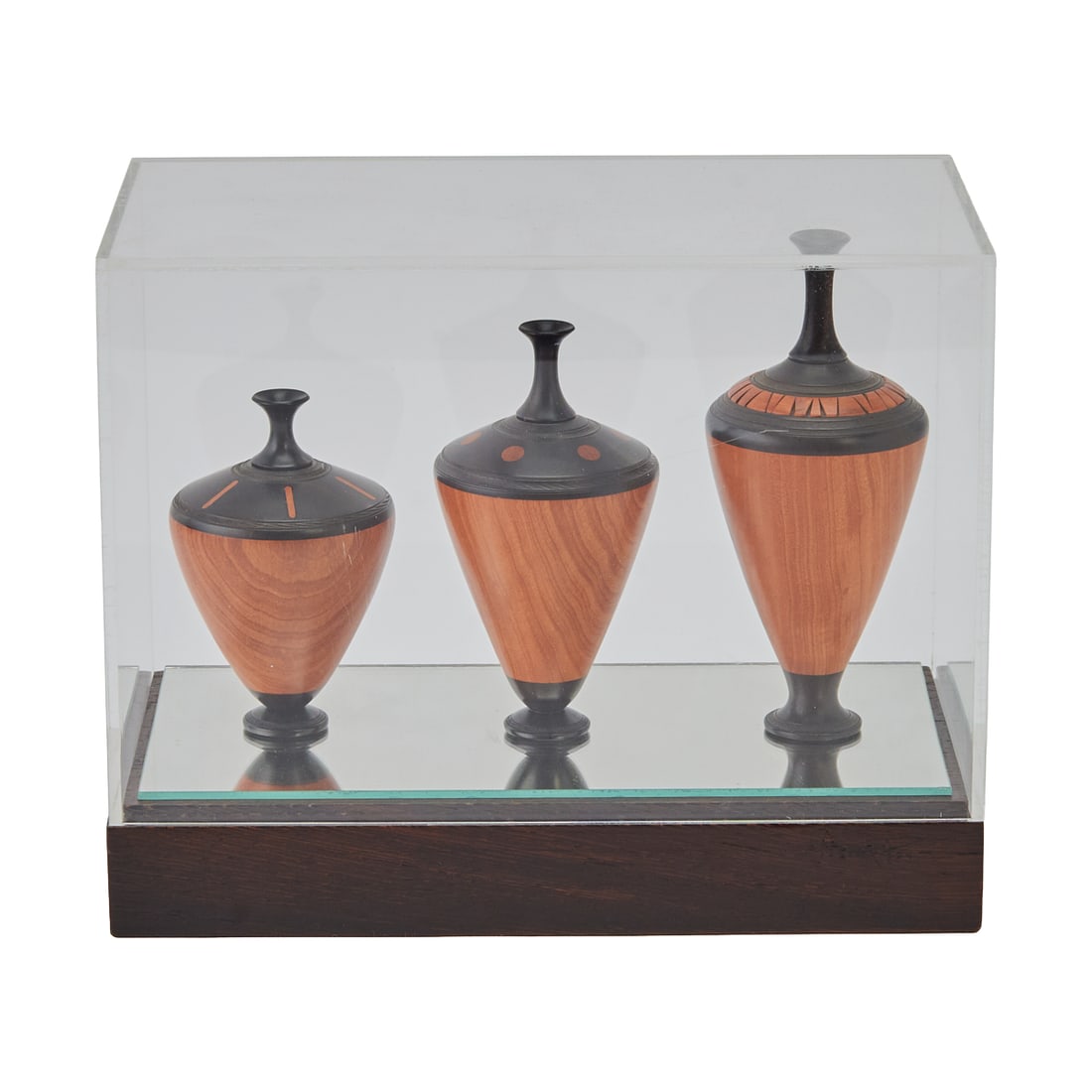 Dennis Stewart, Set of Three Turned Vessels in Case: Dennis Stewart, Set of Three Turned Vessels in Case, canopic in form, the case acrylic{Approximate dimensions: 7” H. x 9” W. x 5 1/2” D.}.