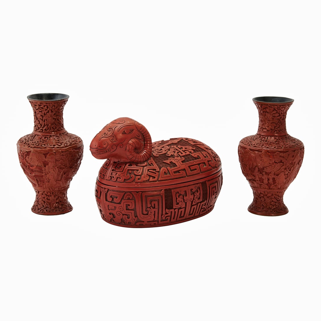 Three Chinese Carved Cinnabar Lacquer Items: Three Chinese Carved Cinnabar Lacquer ItemsConsisting of two cinnabar lacquer vases and a carved cinnabar lacquer box and cover in the form of a recumbent ram. The vases each with a flaring neck and