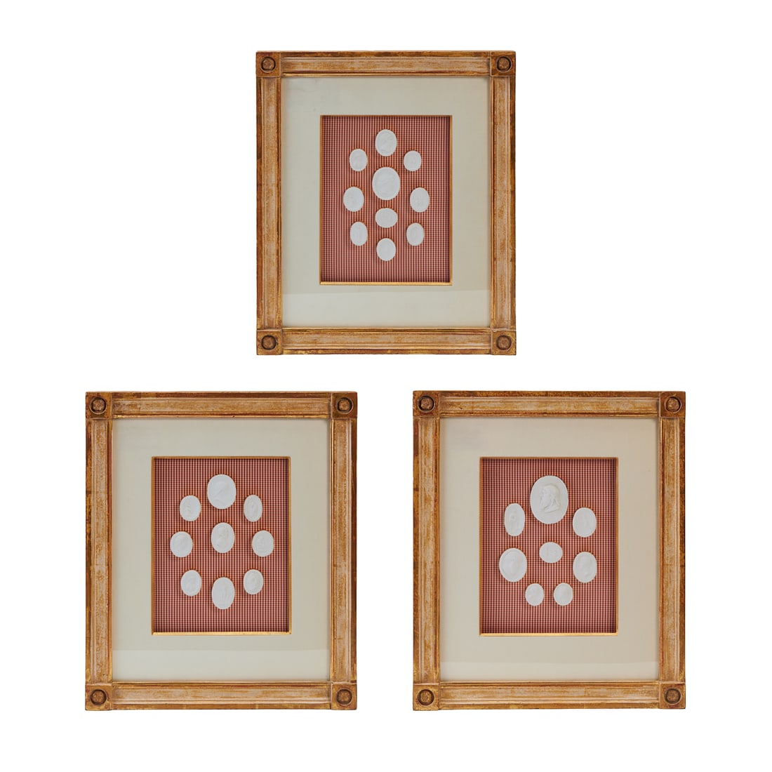 Four Framed Plaster Medallions After the Antique, mounted onto gingham backing, under white mats,: Four Framed Plaster Medallions After the Antique, mounted onto gingham backing, under white mats, within giltwood frames.{Approximate dimensions: 13" H.x 10 " W. x 2" D.}.