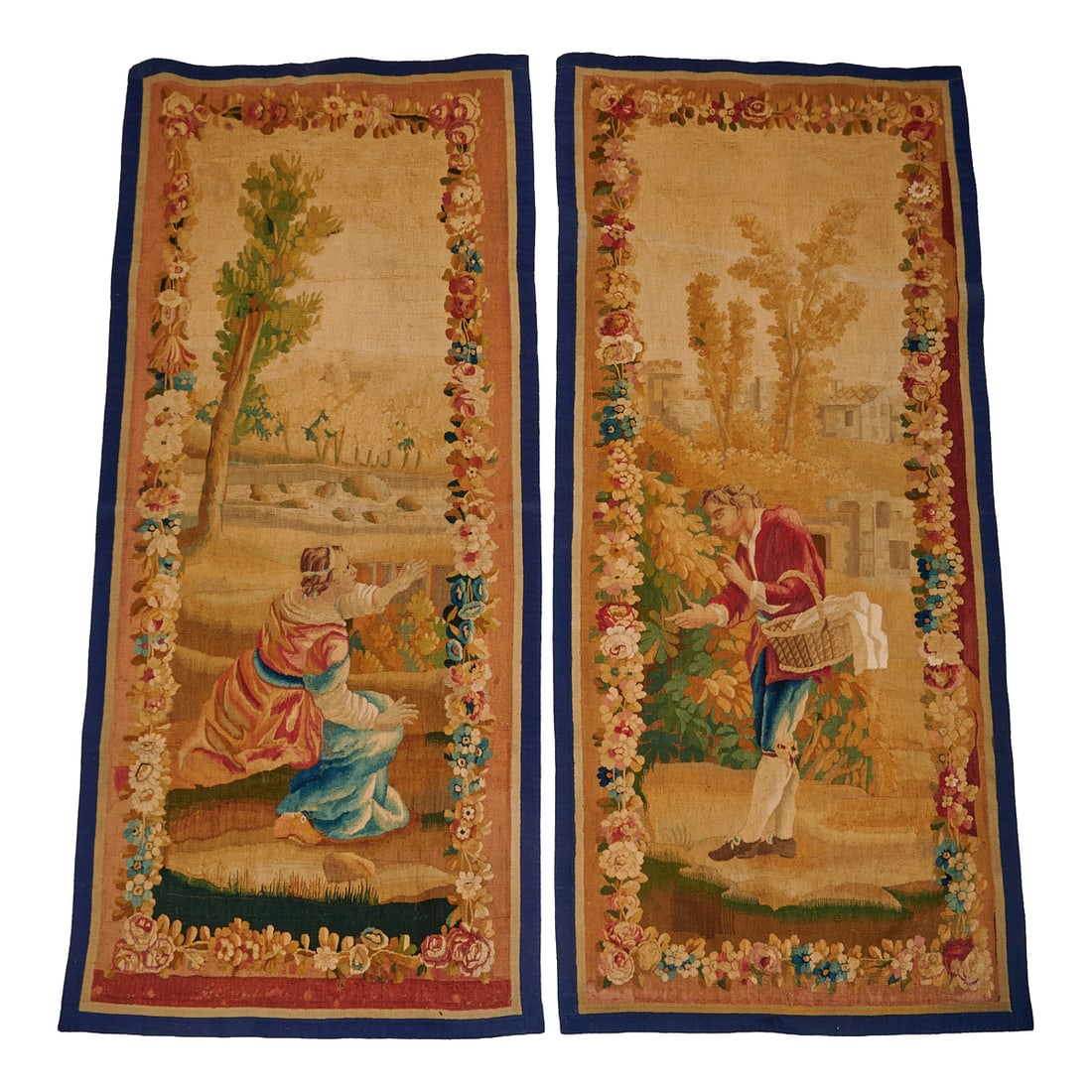 Pair of Aubusson Tapestry Panels. Each rectangular panel featuring a male holding a basket or a: Pair of Aubusson Tapestry Panels. Each rectangular panel featuring a male holding a basket or a female figure seated in the fields in the foreground or trees and foliage in the background within a flo